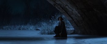 Movie still from “Fantastic Beasts and Where to Find Them” (2016), directed by David Yates – A woman sitting on the ground under a bridge at night; Wide shot, High angle