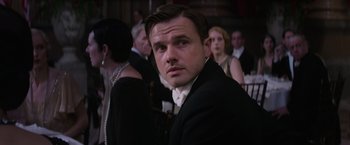 Movie still from “Fantastic Beasts and Where to Find Them” (2016), directed by David Yates – A man in a suit and tie in front of a group of people; Close Up shot, Over the shoulder angle