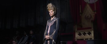 Movie still from “Fantastic Beasts and Where to Find Them” (2016), directed by David Yates – A woman in a dress and a crown standing in front of an audience; Medium shot, Low angle
