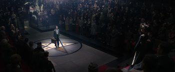 Movie still from “Fantastic Beasts and Where to Find Them” (2016), directed by David Yates – A man standing in front of a crowd of people in front of an audience; Wide shot, High angle