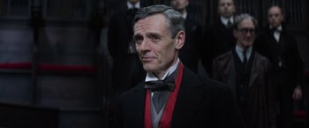 An older man wearing a suit and a red bow tie