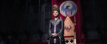 Movie still from “Fantastic Beasts and Where to Find Them” (2016), directed by David Yates – A woman in a costume stands in front of a building; Medium shot, Low angle
