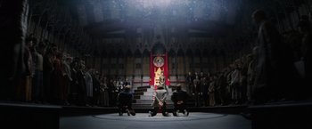Movie still from “Fantastic Beasts and Where to Find Them” (2016), directed by David Yates – A group of people standing on a stage in front of an audience; Extreme Wide shot, Low angle
