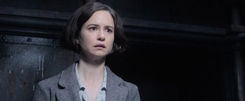 Movie still from “Fantastic Beasts and Where to Find Them” (2016), directed by David Yates – A woman with short hair is looking at the camera; Close Up shot, Over the shoulder angle
