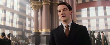 Movie still from “Fantastic Beasts and Where to Find Them” (2016), directed by David Yates – A man in a suit and tie standing in front of pillars; Close Up shot, Low angle