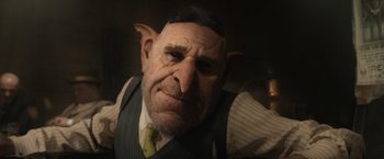 Movie still from “Fantastic Beasts and Where to Find Them” (2016), directed by David Yates – An old man with a beard and a suit and tie on; Close Up shot, Low angle