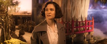 Movie still from “Fantastic Beasts and Where to Find Them” (2016), directed by David Yates – A woman in a brown jacket standing in front of a red fence; Close Up shot, Over the shoulder angle