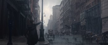 Movie still from “Fantastic Beasts and Where to Find Them” (2016), directed by David Yates – A man in a long coat and hat is on a street corner; Extreme Wide shot, High angle