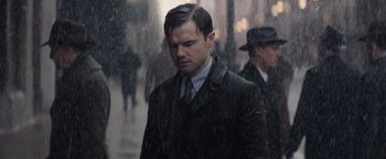 Movie still from “Fantastic Beasts and Where to Find Them” (2016), directed by David Yates – A man wearing a suit and tie standing in the rain; Close Up shot, Low angle