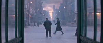 Two men are walking down the street in the fog