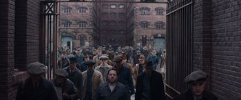 Movie still from “Fantastic Beasts and Where to Find Them” (2016), directed by David Yates – A group of men walking down a street in front of brick buildings; Extreme Wide shot, High angle