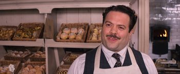 Movie still from “Fantastic Beasts and Where to Find Them” (2016), directed by David Yates – A man standing in front of a display of baked goods; Close Up shot, Over the shoulder angle
