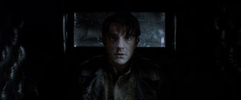 Movie still from “Fantastic Beasts: The Crimes of Grindelwald” (2018), directed by David Yates – A man in a dark room looking at the camera; Close Up shot, Low angle