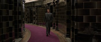 Movie still from “Fantastic Beasts: The Crimes of Grindelwald” (2018), directed by David Yates – A man in a suit and tie walking down a purple path; Wide shot, Low angle