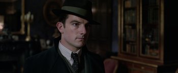 Movie still from “Fantastic Beasts: The Crimes of Grindelwald” (2018), directed by David Yates – A man wearing a hat and a suit; Close Up shot, Low angle