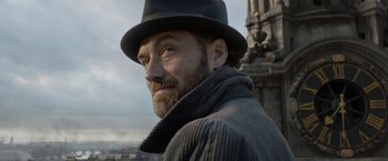 Movie still from “Fantastic Beasts: The Crimes of Grindelwald” (2018), directed by David Yates – A man with a beard wearing a hat and a jacket; Close Up shot, Low angle