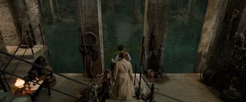 Movie still from “Fantastic Beasts: The Crimes of Grindelwald” (2018), directed by David Yates – Two people are standing on a bridge over a river; Wide shot, High angle