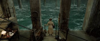 Movie still from “Fantastic Beasts: The Crimes of Grindelwald” (2018), directed by David Yates – An old woman is walking down the stairs in front of the ocean; Extreme Wide shot, High angle