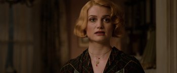 Movie still from “Fantastic Beasts: The Crimes of Grindelwald” (2018), directed by David Yates – A woman with blonde curly hair wearing a necklace; Close Up shot, Over the shoulder angle