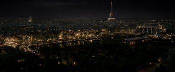 Movie still from “Fantastic Beasts: The Crimes of Grindelwald” (2018), directed by David Yates – A view of a city at night with a tower in the background; Extreme Wide shot, High angle