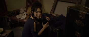 Movie still from “Fantastic Beasts: The Crimes of Grindelwald” (2018), directed by David Yates – A young woman holding a fan in a room; Medium shot, High angle