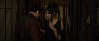 Movie still from “Fantastic Beasts: The Crimes of Grindelwald” (2018), directed by David Yates – A man and a woman standing next to each other in front of a cage; Medium shot, Low angle