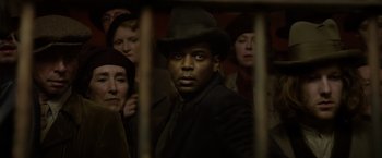 Movie still from “Fantastic Beasts: The Crimes of Grindelwald” (2018), directed by David Yates – A group of people standing next to each other in a room; Close Up shot, Over the shoulder angle