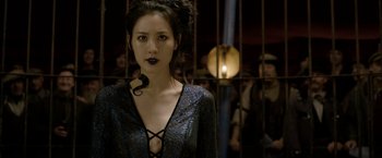 Movie still from “Fantastic Beasts: The Crimes of Grindelwald” (2018), directed by David Yates – A woman with a snake in her mouth standing in front of a cage; Close Up shot, Over the shoulder angle