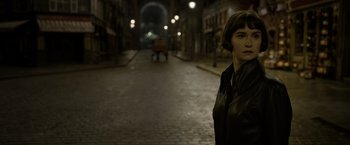 Movie still from “Fantastic Beasts: The Crimes of Grindelwald” (2018), directed by David Yates – A woman standing on a brick street at night; Close Up shot, High angle