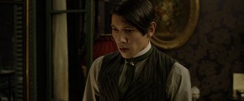 Movie still from “Fantastic Beasts: The Crimes of Grindelwald” (2018), directed by David Yates – A man in a suit and tie looking to his left; Close Up shot, Over the shoulder angle