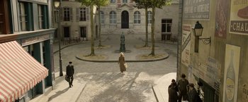 Movie still from “Fantastic Beasts: The Crimes of Grindelwald” (2018), directed by David Yates – An old woman walking down the street in a courtyard; Extreme Wide shot, High angle