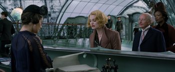 Movie still from “Fantastic Beasts: The Crimes of Grindelwald” (2018), directed by David Yates – A woman sitting in front of a mirror in front of a building; Medium shot, Low angle