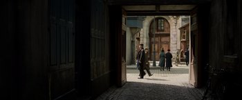 Movie still from “Fantastic Beasts: The Crimes of Grindelwald” (2018), directed by David Yates – A group of people walking down a street; Extreme Wide shot, High angle