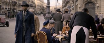 Movie still from “Fantastic Beasts: The Crimes of Grindelwald” (2018), directed by David Yates – A group of people sitting at a table with food; Wide shot, Over the shoulder angle