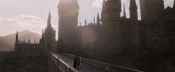 Movie still from “Fantastic Beasts: The Crimes of Grindelwald” (2018), directed by David Yates – A couple of people walking on top of a bridge near a castle; Extreme Wide shot, High angle