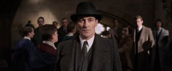 Movie still from “Fantastic Beasts: The Crimes of Grindelwald” (2018), directed by David Yates – A man wearing a suit and a black hat; Medium shot, Low angle
