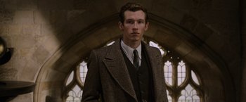 Movie still from “Fantastic Beasts: The Crimes of Grindelwald” (2018), directed by David Yates – A man in a suit and tie standing in front of a window; Close Up shot, Low angle