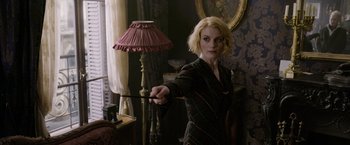Movie still from “Fantastic Beasts: The Crimes of Grindelwald” (2018), directed by David Yates – A woman holding a wand standing in front of a floor lamp; Medium shot, Over the shoulder angle