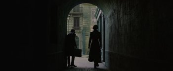 Movie still from “Fantastic Beasts: The Crimes of Grindelwald” (2018), directed by David Yates – A man and a woman walking through an archway; Wide shot, Over the shoulder angle