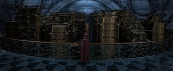 Movie still from “Fantastic Beasts: The Crimes of Grindelwald” (2018), directed by David Yates – A woman in a purple robe standing in front of a bunch of boxes; Wide shot, High angle