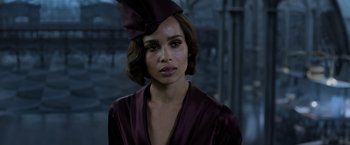 Movie still from “Fantastic Beasts: The Crimes of Grindelwald” (2018), directed by David Yates – A woman in a purple dress with a purple hat on her head; Close Up shot, Over the shoulder angle