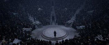 Movie still from “Fantastic Beasts: The Crimes of Grindelwald” (2018), directed by David Yates – A crowd of people standing in a circle with a man in a black coat; Extreme Wide shot, High angle