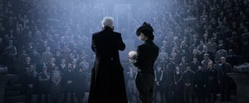 Movie still from “Fantastic Beasts: The Crimes of Grindelwald” (2018), directed by David Yates – Two people in front of a crowd of people; Wide shot, Over the shoulder angle