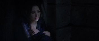 Movie still from “Fantastic Beasts: The Crimes of Grindelwald” (2018), directed by David Yates – A woman sitting in the dark with her hands on her chest; Close Up shot, High angle