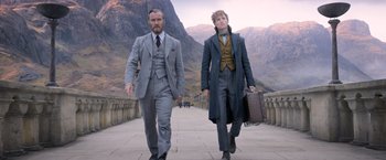 Movie still from “Fantastic Beasts: The Crimes of Grindelwald” (2018), directed by David Yates – Two men walking down a stone walkway with mountains in the background; Medium shot, Low angle
