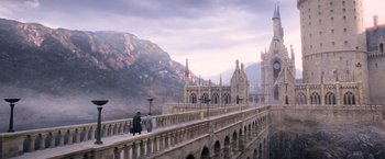 Movie still from “Fantastic Beasts: The Crimes of Grindelwald” (2018), directed by David Yates – Two people are walking on a bridge over a river; Extreme Wide shot, High angle