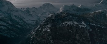 Movie still from “Fantastic Beasts: The Secrets of Dumbledore” (2022), directed by David Yates – A mountain range with snow on top of it and trees in the background; Extreme Wide shot, High angle