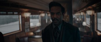 Movie still from “Fantastic Beasts: The Secrets of Dumbledore” (2022), directed by David Yates – A man in a suit and tie standing in front of a window; Close Up shot, Over the shoulder angle