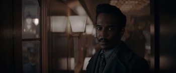 Movie still from “Fantastic Beasts: The Secrets of Dumbledore” (2022), directed by David Yates – A man in a suit and tie standing next to a wall; Close Up shot, Over the shoulder angle