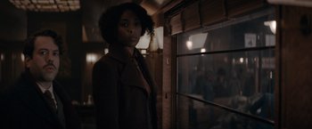 Movie still from “Fantastic Beasts: The Secrets of Dumbledore” (2022), directed by David Yates – A woman standing in front of a window in a dark room; Medium shot, Over the shoulder angle